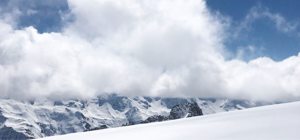 Snowy Swiss mountains with fluffy white clouds in the blue sky