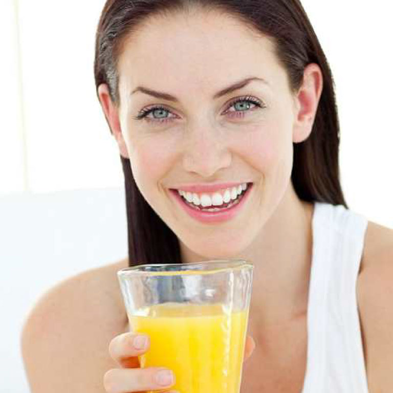 Smiling brunette woman with glass of orange juice