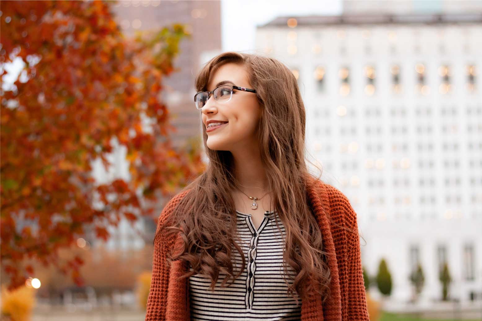 Young girl with glassess and braces looking to the side and smiling